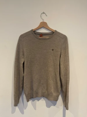 Beige merinoulltröja från Morris - Säljer en lite schysstare beige tröja från Morris i 100% merinoull. Tröjan har rund halsringning, diskret logga broderad på bröstet. Perfekt för dig som gillar klassisk och enkel stil.   Storleken var M men den är krympt till XS!