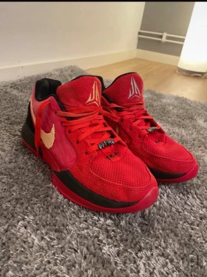 Ja 2 nightmare  - Säljer ett par röda ja 2 nightmare med gul swoosh på sidan och svart detalj vid hälen. Skorna har väldigt bra prestation på basketplanen i alla kategorier. snörning, mesh och mocka på ovansidan samt en platt sula med mönstrad undersida. Logga på plösen och coola detaljer på snörningen. Perfekt för dig som gillar färgstarka sneakers.
