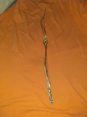 Guldigt armbandsur från Carlude - Säljer ett snyggt armbandsur från Carlude med guldfärgad urtavla och flera flätade och kedjade armband i guldton. Uret har quartz-verk och armbandet har dekorativa detaljer och metalliska inslag som ger en cool look.