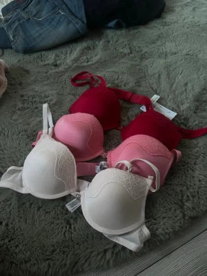 BH! - Säljer tre push up bh:ar i storlek 75A/ 34A i ljusrosa, rosa och röd färg från primark. De är helt oanvända!