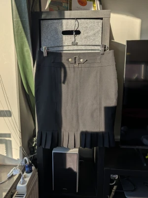 Svart kortkjol med plisserad kant Orsay - Säljer en svart kortkjol från Orsay med snygg plisserad kant längst ner och dekorativt bälte i midjan. Kjolen har en klassisk, rak passform och är perfekt för dig som gillar stilrena detaljer. Materialet känns mjukt och följsamt.