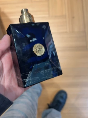 Stilren Versace parfymflaska - Snygg och lyxig parfym från Versace med mörkblå flaska och gulddetaljer. Perfekt för dig som vill sticka ut och visa din stil. Volym och ingredienser syns ej på bilderna.