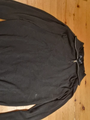 Svart stickad polotröja med half zip - Svart stickad polotröja från Jack & Jones  med half zip-dragkedja i halsen. Tröjan har långärmade och ribbade muddar vid ärmslut och nederkant. Perfekt för lager-på-lager och chill höst- och vinterstil.