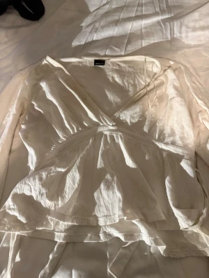 Vit bluss i linne🐑🥥🌟 - En blus i linne tyg. Den är ganska tunn i materialet och faller fint över kroppen. Den har 2 snören fastsydda som man knyter samman backtill till en rosett för en fin detalj där back. Perfekt att ha i vardagen men också vid vissa mer uppklädda tillfällen.🥥🌟✨