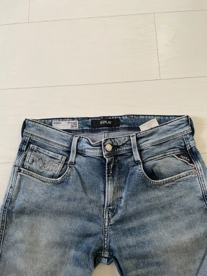 Replay Anbass ljusblå jeans - Säljer ett par Replay Anbass jeans i ljusblå tvätt med klassisk femficksdesign och snygga detaljer på bakfickorna. Jeansen har smal passform och är tillverkade i mjukt jeansmaterial med stretch för extra komfort. Perfekt för dig som gillar stilrena och moderna jeans.W30 L32