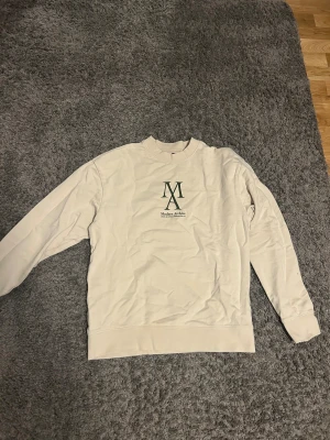 Beige sweatshirt från Jack & Jones M - Säljer en beige sweatshirt från Jack & Jones med trycket 'Modern Archive' och en stor grön logga på bröstet. Tröjan har rund hals, långa ärmar och är gjord i mjuk bomull. Perfekt basic-plagg med clean look och relaxed fit.