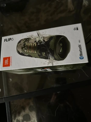 JBL Flip 6 Bluetooth-högtalare - JBL Flip 6 portabel Bluetooth-högtalare i camo-design. Vattentät, upp till 12 timmars batteritid och kraftfullt ljud. Högtalaren och originalkartongen ser ut att vara i mycket gott skick, inga synliga defekter eller slitage. Perfekt för både inomhus och utomhusbruk.HELT NY , endast öppnad för o kort . 