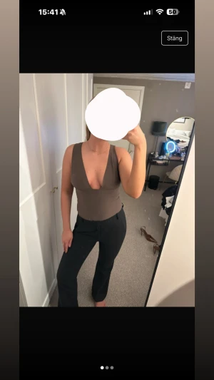 Brun ärmlös linnetopp med djup v-ringning - Snygg brun linnetopp med breda axelband och djup v-ringning framtill. Toppen är figurnära och har en stilren, enkel design utan synliga detaljer. Perfekt för dig som gillar minimalistisk stil och vill ha en topp som framhäver siluetten.