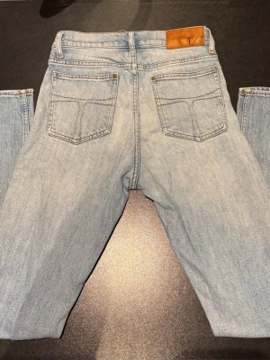 Ljusblå jeans från Tiger of Sweden - Snygga ljusblå jeans från Tiger of Sweden med klassisk femficksdesign och bruna sömmar. Jeansen har rak passform och normal midja, tillverkade i mjukt denimtyg. Perfekta för dig som gillar stilrena och tidlösa jeans. Storlek 28:32