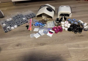 Stort kit med nagelprodukter, dekoration, uv lampa och slipfläkt  - Allt du behöver för att bygga fina gelenaglar! Ett omfattande nagelset innehållande en UV-lampa, fläkt för slipdamm, nagelgel i flertalet färger, flera primer och toplack, 3 burkar nagelfolie, nagelfilar, flera penslar, glitter, tatueringar, bokstäver och andra dekorationer. En del burkar är nästan fulla, en del halvfulla och några har ca en fjärdedel kvar! Flaskorna med primer och toplack är nästan fulla!