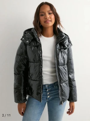 Svart glansig pufferjacka med huva - Säljer en svart, glansig pufferjacka!😊Den ser ut som helt ny skick och har knappt används då jag har för många jackor hemma😫Skicka till mig och du vill ha riktiga bilder då dessa bilder är från Nelly hemsida💕(öppen för priset)