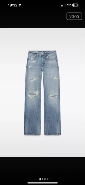 Lågmidjade ljusblå wide jeans med slitningar - Säljer ett par lågmidjade jeans i ljusblå tvätt med breda ben och slitna detaljer på låren och knäna. Modellen har klassisk femficksdesign och är tillverkad i jeansmaterial. Perfekt för dig som gillar en avslappnad och trendig look.