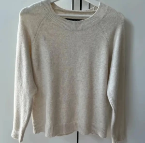 Beige stickad tröja från Vero Moda - Mysig beige stickad tröja från Vero Moda i storlek M. Tröjan har rund hals, ribbade muddar vid ärmslut och nederkant samt långärmad passform.