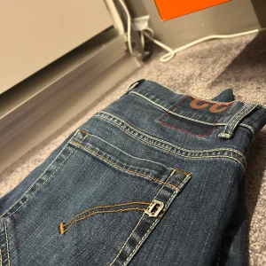 Dondup jeans jeans blå denim - Snygga Dondup George  jeans i klassisk blå denim med kontrastsömmar och detaljerad fickdesign. Modellen har en slim passform och raka ben, med diskret dondup -logga på bakfickan. Perfekt för dig som gillar stilrena och moderna jeans. Kan passa 31