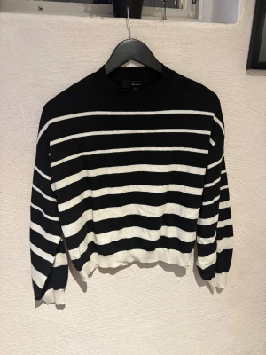 Svartvit randig stickad tröja Vero Moda - Säljer en svart och vit stickad tröja från Vero Moda i storlek XS. Tröjan har ett klassiskt randigt mönster, rund hals och långa ärmar med ribbade muddar. Perfekt för dig som gillar enkel och stilren design med lite edge.