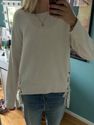 Vit stickad tröja med snörning - Säljer en vit stickad tröja med snygg snörningsdetalj i sidorna. Tröjan har långärmade och ribbad struktur 🩷🩷 Så fin! Meddela för frågor/diskussion💕 