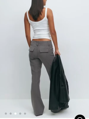 Grå kostymbyxor med bootcut - Snygga grå kostymbyxor med bootcut-snitt och låg midja. Säljer då de inte kommer till användning längre, köpta nyligen. 