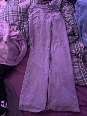 Grå mjukisbyxor med vida ben - Säljer ett par grå mjukisbyxor med breda, raka ben och dragsko i midjan. Byxorna har en avslappnad passform och är perfekta för chill dagar. Tillverkade i mjukt material som känns skönt mot huden.