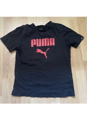 Svart Puma t-shirt  - Svart t-shirt från Puma med stor röd logga och puma-tryck på bröstet. Storlek XS ish 