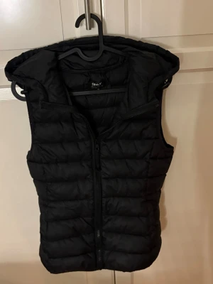 Svart dunväst från ONLY med huva - Jag säljer denna super snygga dunbästen från only, den har luva och fickor och är sitter super bra på! Köp nu jag postar snabbt!!💕💕