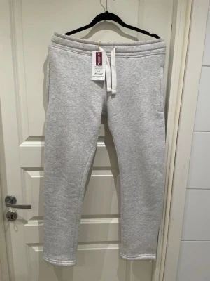 Ljusgrå mjukisbyxor Russedress XS - Ljusgrå sweatpants från Russedress i unisexmodell, storlek XS. Byxorna har snörning i midjan och är tillverkade i mjukt bomullsmaterial med Oeko-Tex certifiering. Perfekta för chill dagar och har en enkel, stilren look.helt nya har aldrig använts 