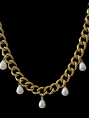 Guldpläterat halsband med droppformade pärlor - Elegant halsband i guldpläterat rostfritt stål – finns även i silverfärgad variant. Matchande örhängen finns i en separat annons.  Smycket är 9 mm brett och har en justerbar längd mellan 38–43 cm, vilket gör att det passar perfekt oavsett stil och tillfälle.. De nickelfria och handgjorda