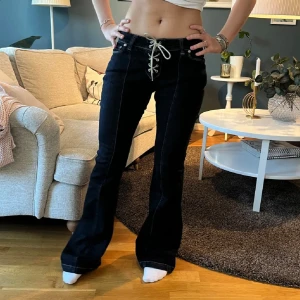 Bootcut jeans med snörning fram - Snygga mörkblå bootcut jeans med låg midja och cool snörning framtill istället för vanlig knapp. Jeansen har klassiska fickor både fram och bak samt markerade sömmar. I storlek w26 från Weekday, men eftersom dom har snörning och är stretchiga kan dom förmodligen passa både lite större och mindre☺️