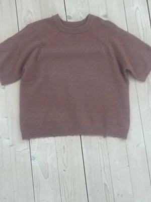 Kortärmad stickad tröja - Mysig stickad tröja från 157 med korta ärmar och rund hals. Tröjan har ribbade muddar vid hals, ärmslut och nederkant. Enkel och stilren design som är lätt att matcha. Den är knappt använd! OBS tröjan är färgen gammelrosa.