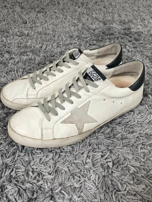 Golden Goose Superstar - Säljer nu dessa riktigt snygga sneakers från Golden Goose!  De är i bra skick men hälarna och sulan är sliten, se bilder, men inget som syns vid användning. Storlek 43.  Nypris runt 4000kr!  Självklart äkta✔️ Hör av dig vid frågor eller funderingar, priset är inte hugget i sten!