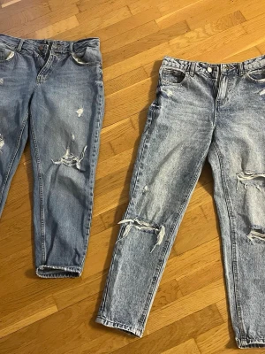 Ljusa blå ripped jeans straight fit - Säljer ett par ljusblå jeans med slitna detaljer och stora ripped hål på benen. Jeansen har en rak passform och klassisk femficksdesign. Perfekt för dig som gillar en avslappnad och trendig stil. Materialet är klassisk jeansbomull.