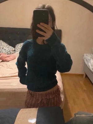 Mörkgrön stickad tröja  - Säljer en mysig mörkgrön stickad tröja med ribbad struktur. Tröjan har rund halsringning och långa ärmar med breda muddar.