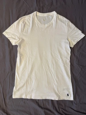 Vit t-shirt från Polo Ralph Lauren - Vit t-shirt från Polo Ralph Lauren i mjuk bomull. Storlek M 175/96A. Trycket på halsen har åkt av i tvätten därav använt skick. Tveka inte att ställa frågor💯