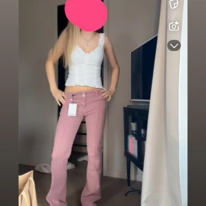 Rosa bootcut jeans från Bershka - Säljer ett par snygga rosa jeans från Bershka i bootcut-modell. Byxorna har låg midja, klassisk femficksdesign och är gjorda i ett mjukt bomullsmaterial. Perfekta för dig som vill ha en trendig och bekväm look.