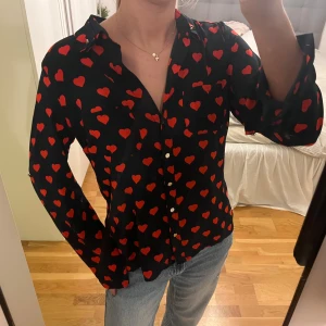 Svart skjorta/blus med röda hjärtan Oasis - Svart skjorta från Oasis med röda hjärtan över hela tyget. 