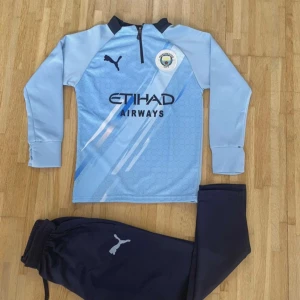 Manchester City långärmad fotbollströja Puma - Manchester City långärmad fotbollströja från Puma i ljusblått med svarta detaljer och klubbmärke på bröstet. Tröjan har halv dragkedja och tryck med Etihad Airways. Materialet är lätt och andas, perfekt för träning eller match.