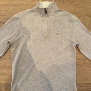Beige half zip tröja från Polo Ralph Lauren - Snygg beige långärmad tröja från Polo Ralph Lauren med half zip och klassisk broderad logga på bröstet. Tröjan är i nyskick och aldrig använd! Storlek S men passar också M.