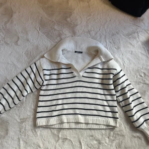 Randig stickad tröja med krage - Vit stickad tröja från Gina Tricot med svarta horisontella ränder och bred krage. Den är i storlek XS
