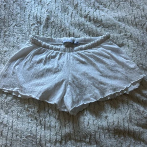 Vita flowy shorts från 157 - Superlätta och luftiga vita shorts från 157 med elastisk midja och vågig kant nertill. Perfekta för varma dagar, tillverkade i mjuk bomull som känns skön mot huden. Enkel och stilren design som är lätt att matcha.