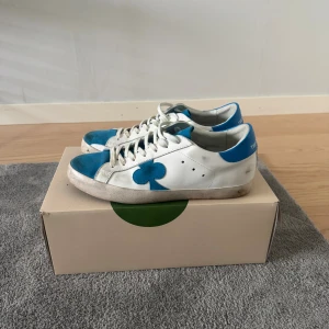 The Gallerist - Snygga sneakers från The Gallerist i vitt skinn med blå detaljer och blå mocka på tån.  Perfekta för dig som gillar unik stil. Skick 9/10 