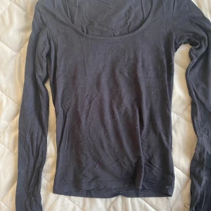 Svart långärmad topp Gina Tricot XS - En svart långärmad topp från Gina Tricot i storlek XS. Toppen har en rundad, djup urringning och är tillverkad i mjuk bomull. Perfekt att styla med jeans eller kjol för en enkel och clean look.