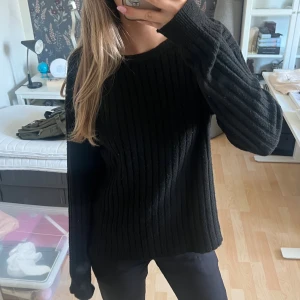 Svart ribbad stickad tröja från Pieces - Svart stickad tröja från Pieces med ribbat mönster. Tröjan har en snygg v-ringning på ena sidan och rund hals på andra, så den kan bäras åt båda hållen. 