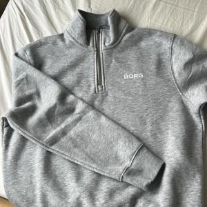 Grå half zip tröja från Björn Borg - Aldrig använd då den var för liten. I ett nytt skick. Ordinarie pris 399kr.