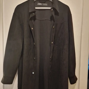 Svart kavaj från Zara i mocka-look - Stilren svart oversize kavaj från Zara i mjuk mocka-liknande material. Perfekt för lager-på-lager och ger en clean vibe till din outfit.