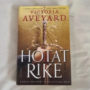 Hotat rike - En fantastisk fantasyromance bok skriven av Victoria Aveyard. Första boken i en ny serie av författaren till Röd Drottning. Endast läst två gånger, bra kvalitet men med några få slitage (se bild), på svenska och för bra pris! Nypris runt 200 kr.