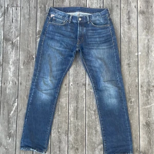 Blå jeans från Denim & Supply Ralph Lauren - 33W 32L. Snygga blå jeans från Denim & Supply Ralph Lauren med klassisk femficksdesign med skön fade och honeycombs. Jeansen har en rak passform och detaljer som kontrastsömmar och patch med amerikansk flagga på backpatchen