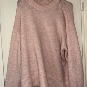 Ljusrosa oversized stickad tröja - Supermysig ljusrosa stickad tröja med oversized passform och bred ribbad kant nedtill och vid ärmsluten. Perfekt för lager-på-lager och chill dagar. Hög rund halsringning och långa ärmar ger en avslappnad vibe.