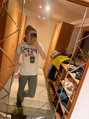 Vit Pepsi Max t-shirt  - Vit t-shirt med handmålat Pepsi Max-tryck både fram och bak. T-shirten har blå krage och röda detaljer på ärmsluten. Klassisk passform och korta ärmar, perfekt för dig som vill sticka ut med en unik look.