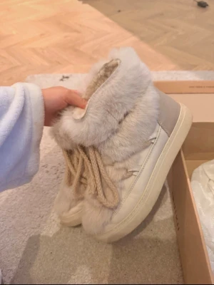 Beige pälsboots från Inuikii - Säljer ett par snygga beige boots från Inuikii. Skorna har en rund tå och platt sula, samt detaljer i skinn och päls. Storlek 39 men skulle mer säga 38, nypris 4000
