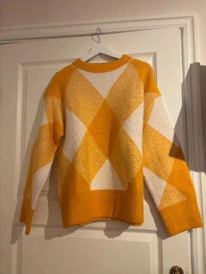 Stickad tröja från Zara  - Snygg stickad tröja med organga och vita färger. Tröjan är från Zara och är i storlek S. 