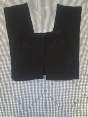 Svarta kostymbyxor med raka ben - Snygga svarta kostymbyxor med klassisk rak passform och bälteshällor. Byxorna har en stilren look och är tillverkade i ett slätt material som ger en dressad känsla. Perfekta för dig som gillar enkel och clean stil.kostade 800kr 